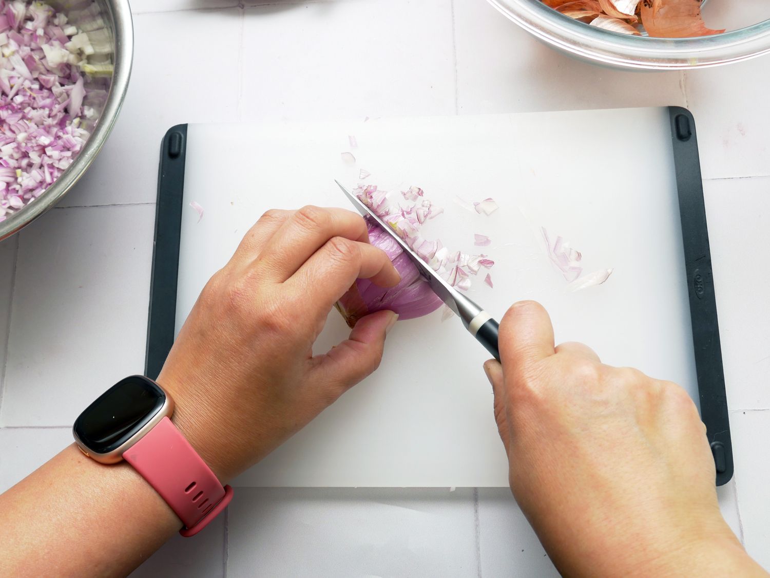 a person using a paring knife to mince shallots