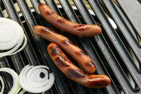 Grilling hot dogs and onion slices on a grill