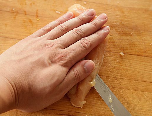 Splitting a boneless, skinless chicken breast in half horizontally.
