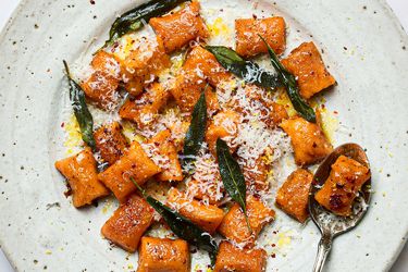 Plate of sweet potato gnocchi topped with grated cheese crispy sage and brown butter