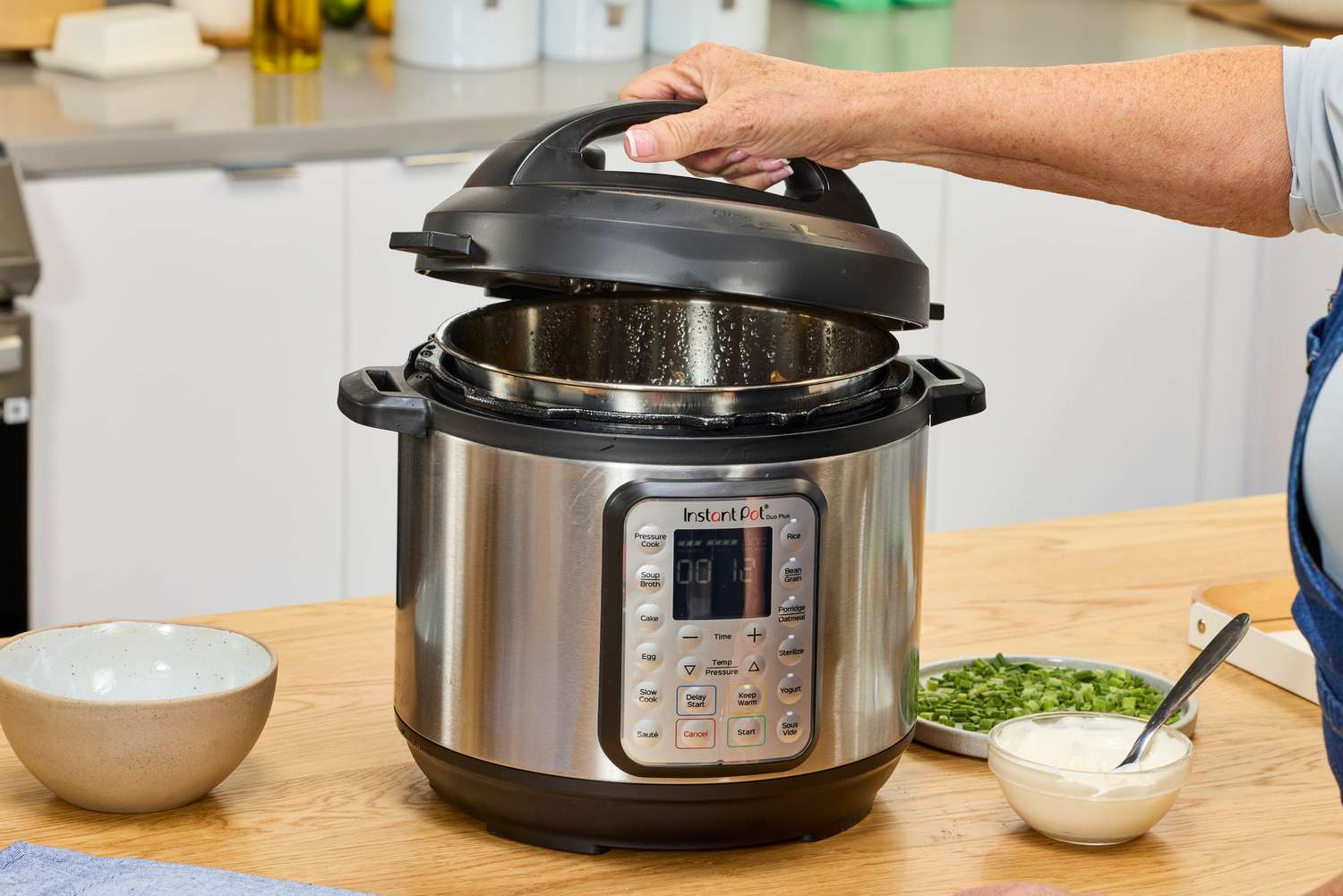 A person removes the lid on the Instant Pot Duo Plus 6-Quart 9-in-1 Pressure Cooker
