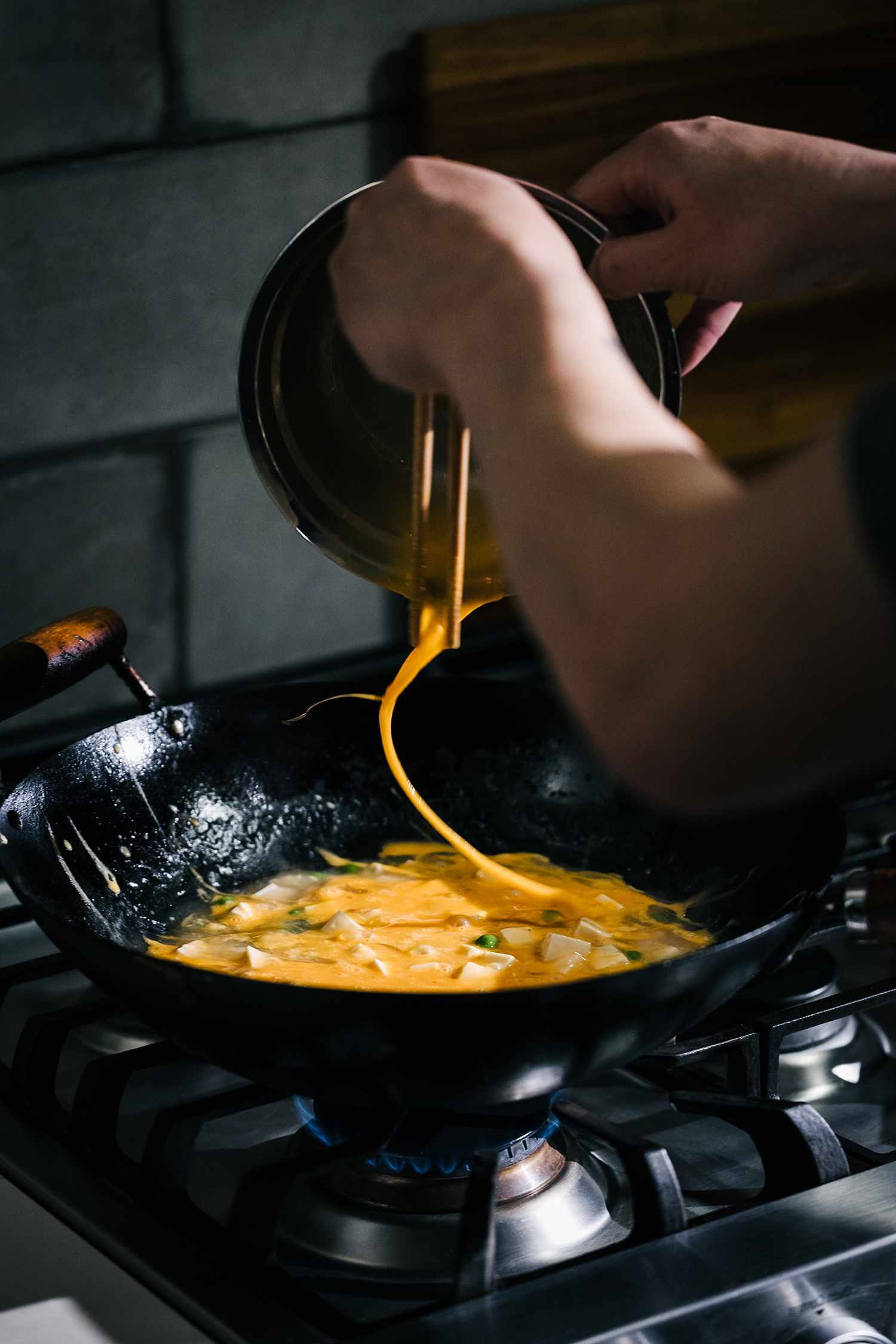 Kenji swishing eggs into a wok using Chopsticks