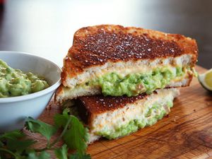 Cross-section view of two halves of a grilled cheese sandwich with guacamole