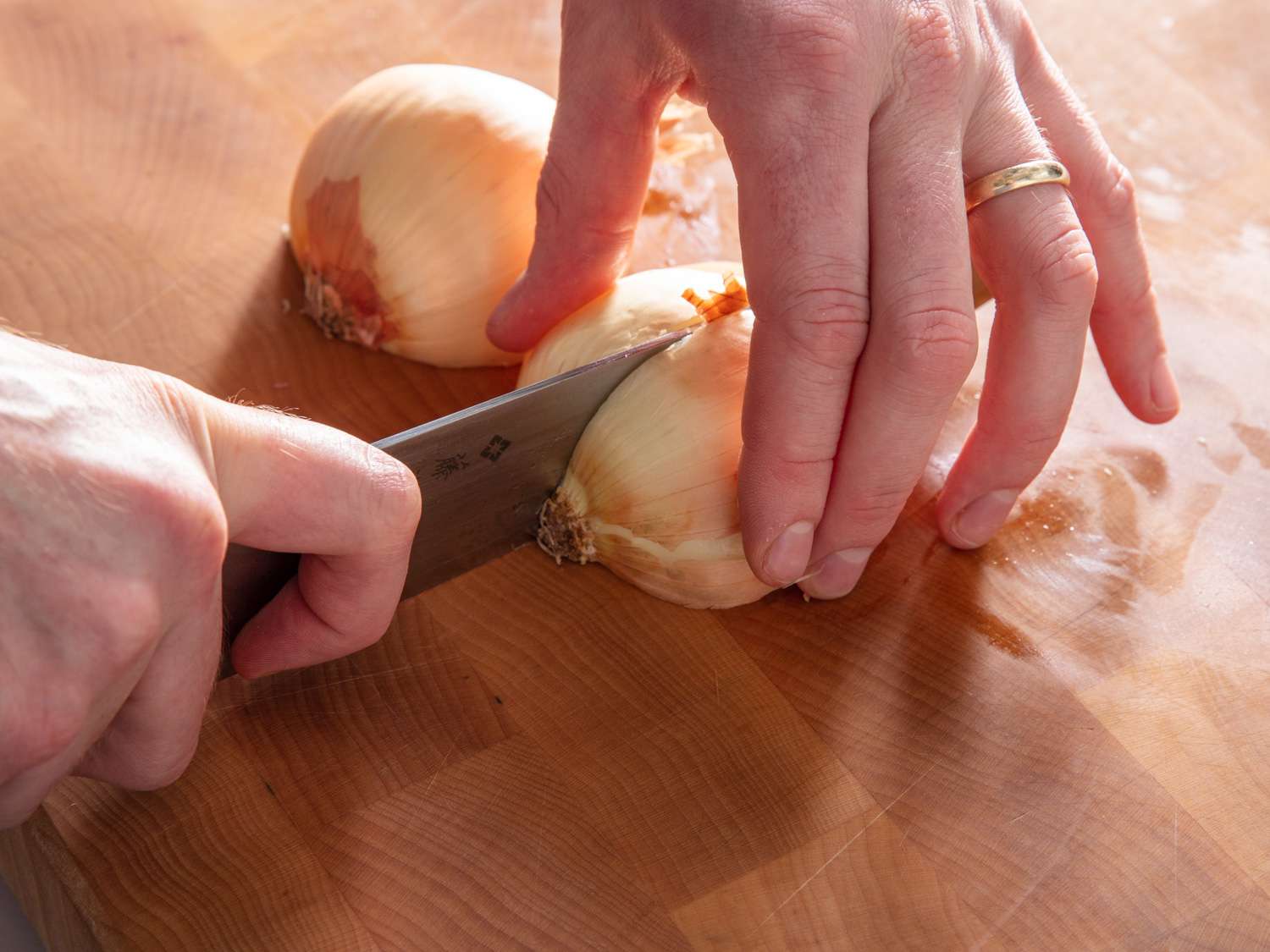 Quartering onion through root end with a chef's knife.