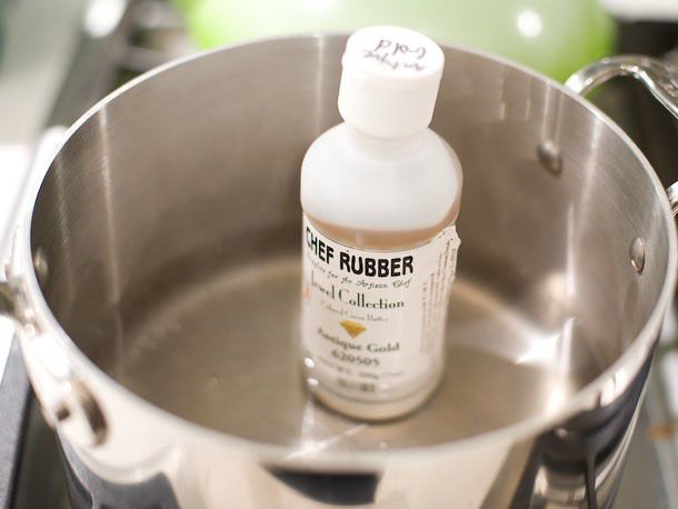 Warming solid cocoa butter in a bottle in a pan of warm water for decorating bonbon tops.