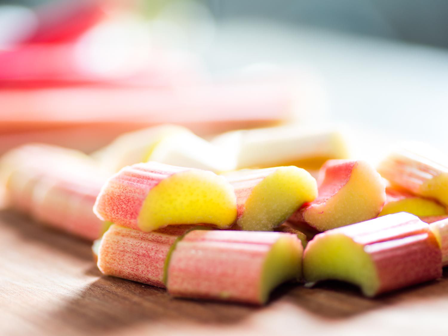 Chopped raw rhubarb segments on a wooden surface