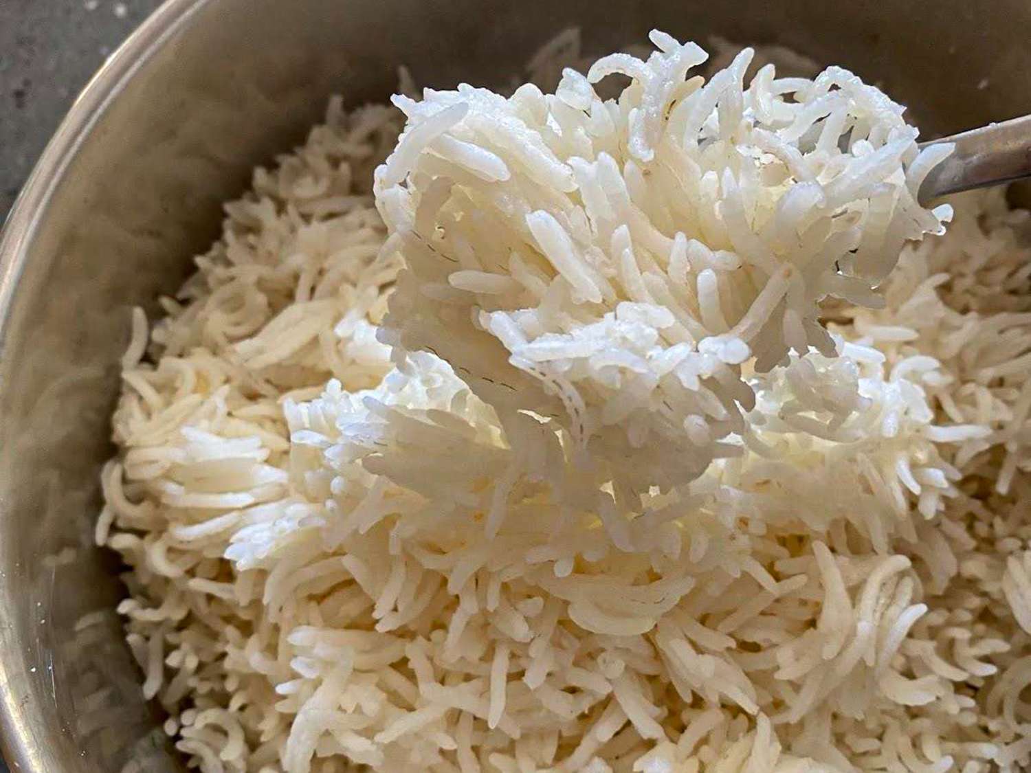A bowl of cooked rice with a spoon scooping some out