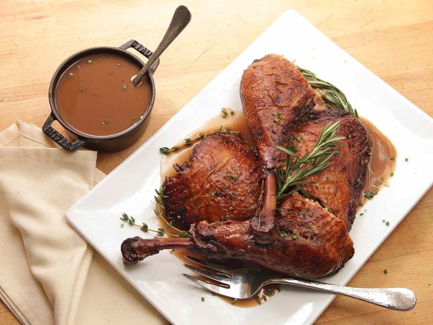 Braised turkey legs on a serving platter, with gravy on the side. 