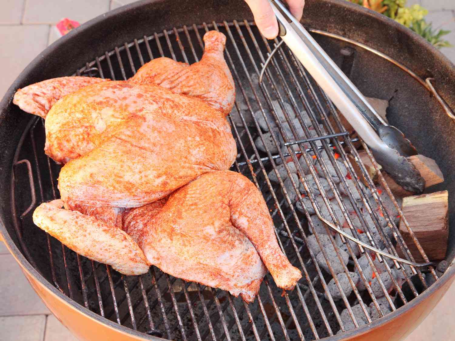 Wood chunks are nestled over the lit charcoal; the turkey is placed on the cool side of the grill.