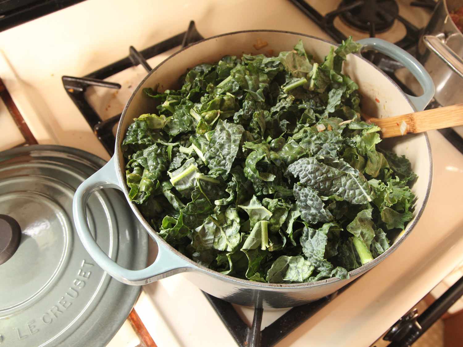 Kale is added to the pan to wilt.