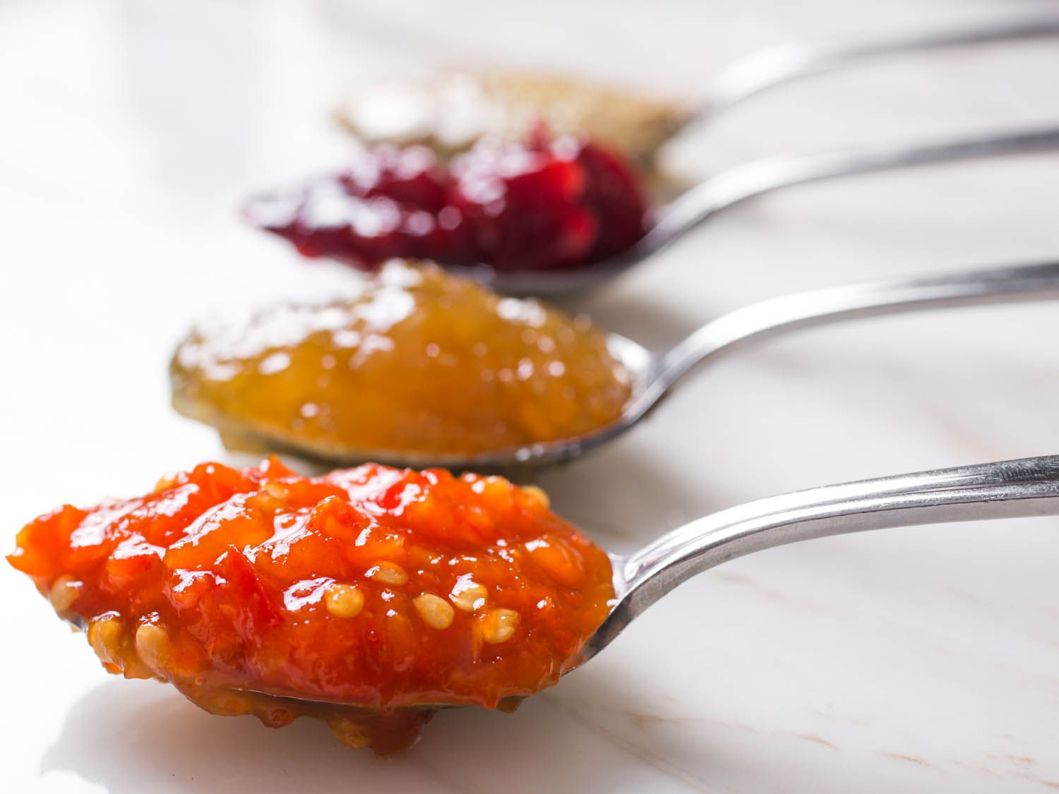 Cheese condiments laid out across four spoons.