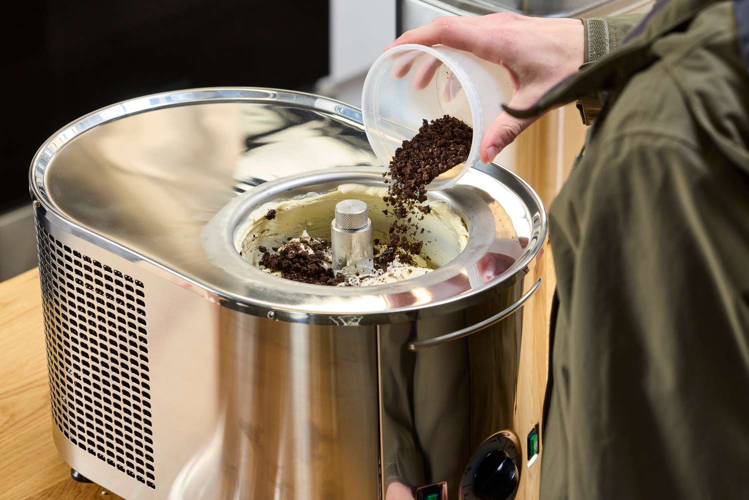 A hand adding toppings to the Lello Musso Lussino 4080 Ice Cream Maker