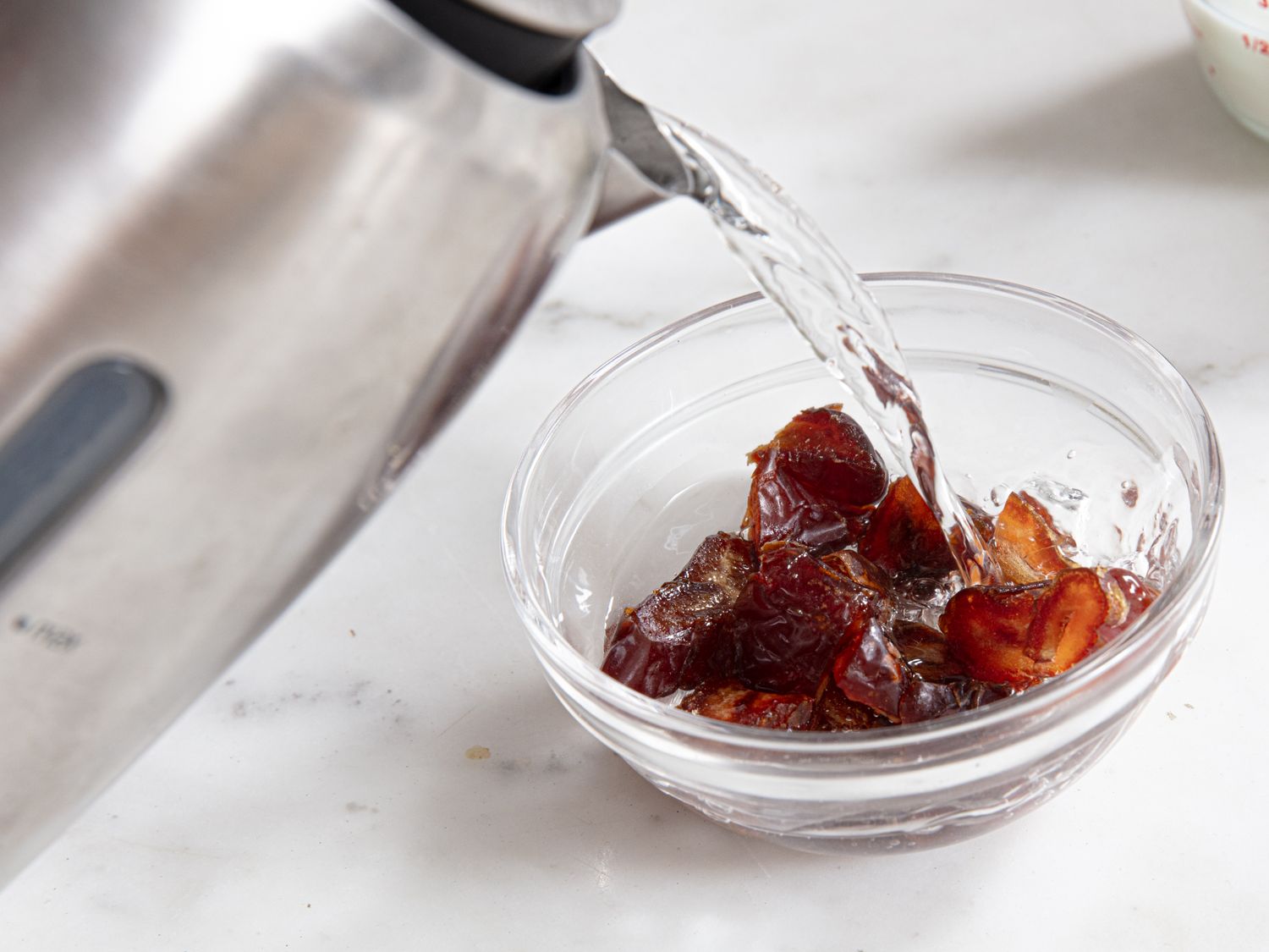 Hot water being poured on dates in a bowl