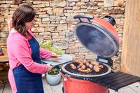A person cooks chicken inside the Kamado Joe Classic II Charcoal Grill