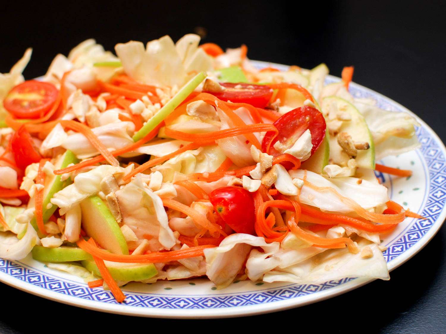 Spicy Cabbage Salad with sliced green apple, julienned carrots, and cherry tomatoes on a platter