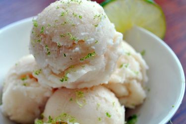Closeup of three scoops of Ginger Beer, Rum, and Coconut Sorbet in a snall bowl. Lime zest has been sprinkled over the sorbet.