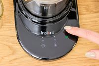 A person tapping the control panel of the Instant milk frother.