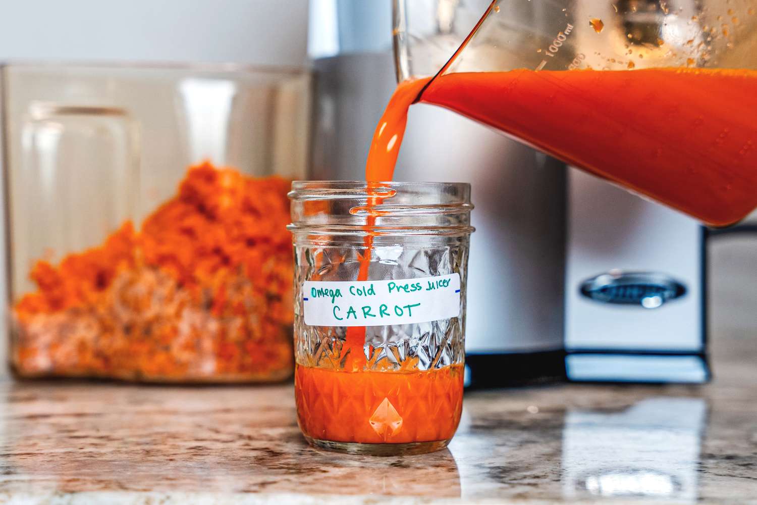 Carrot juice being poured into a mason jar from the Omega VSJ843 juicer