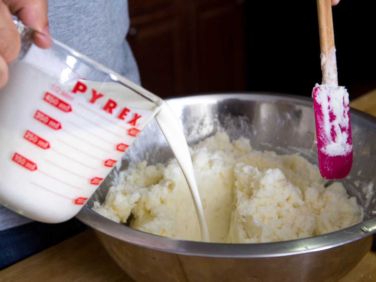 Pouring cream into bowl of mashed potatoes.