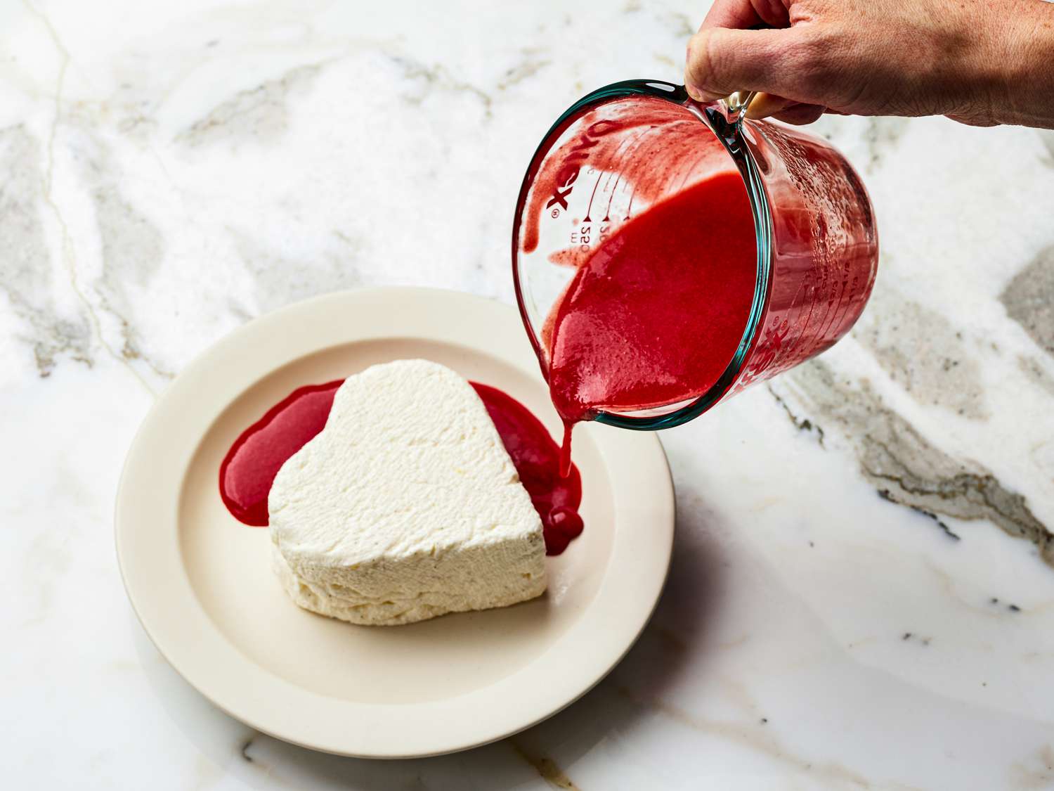 Overhead view of pouring sauce on to plate with mold