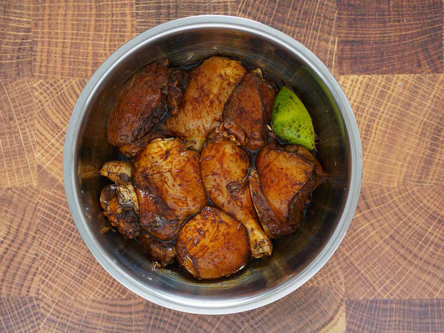 Chicken pieces marinating in dark soy and browning sauce mixture.