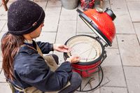 A person places the grill inside the Kamado Joe KJ13RH 13.5 inch Joe Jr. Charcoal Grill