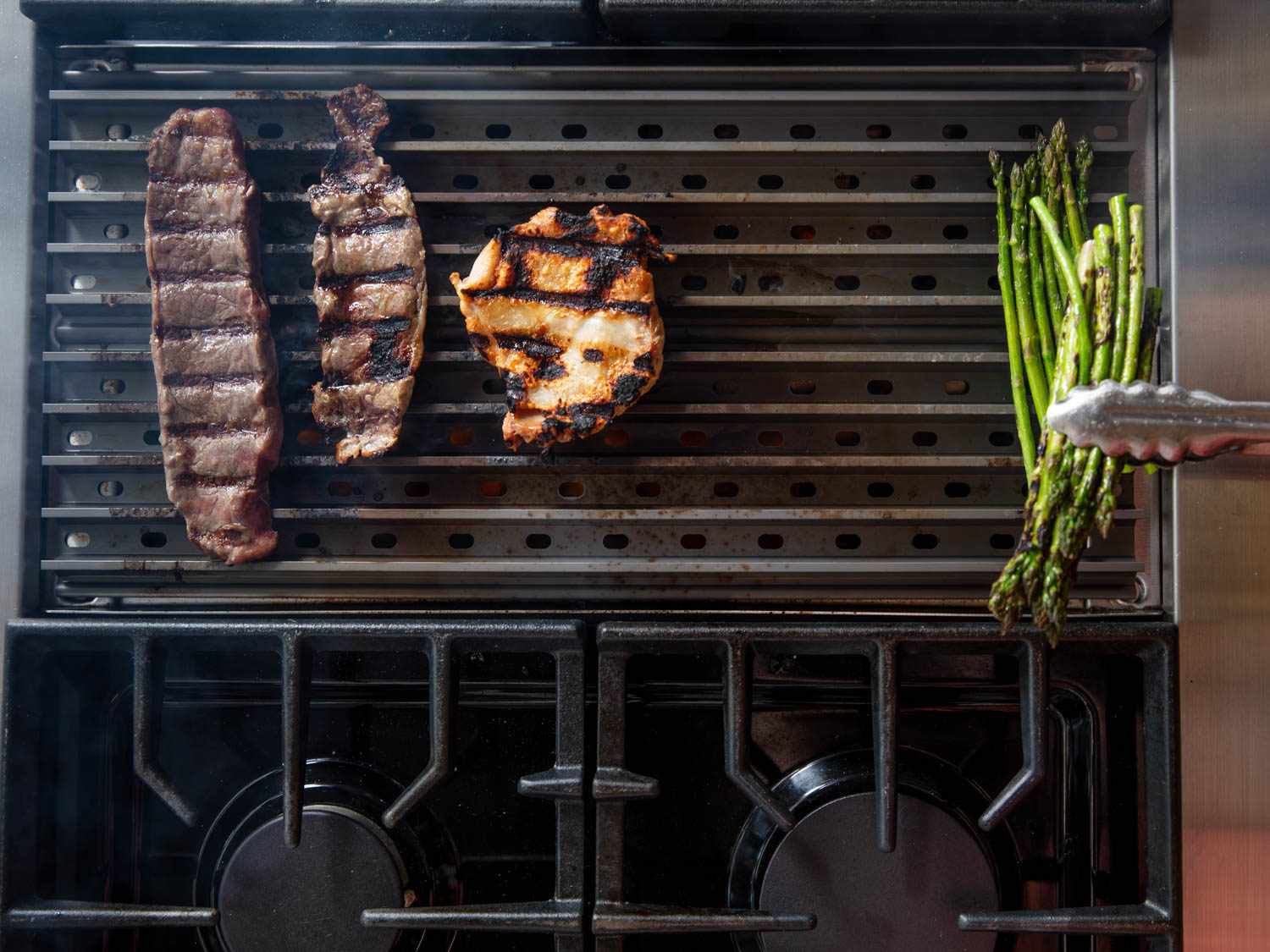 Pieces of meat and vegetables on the grill grate, showing even browning all over regardless of grill position