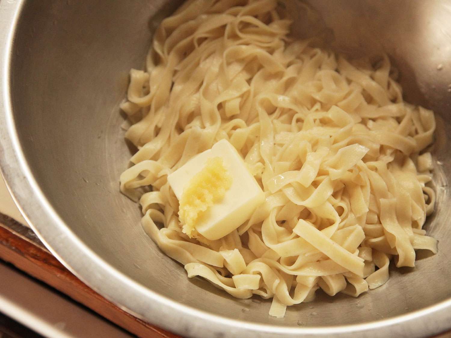 Adding butter to just cooked pasta.