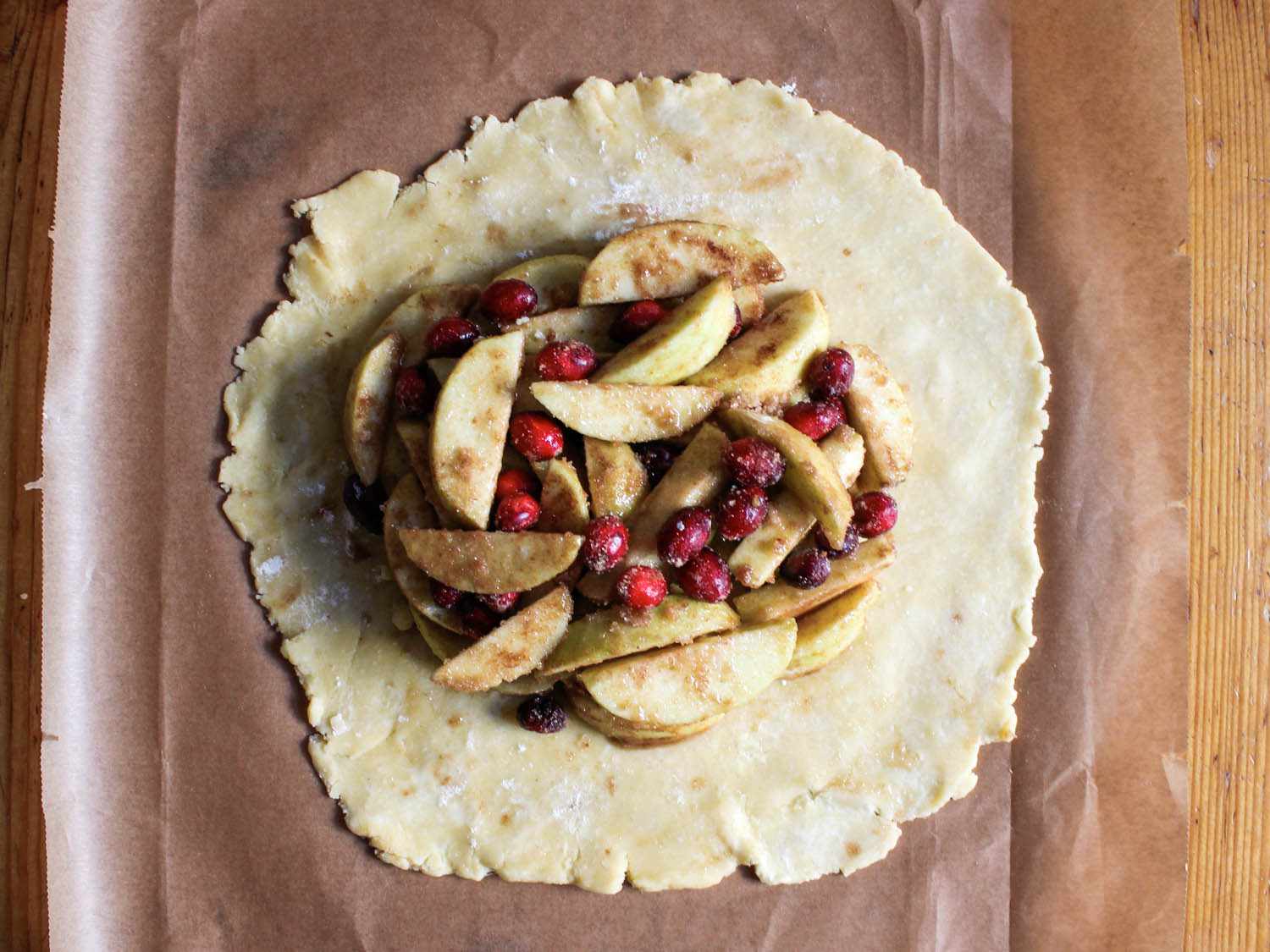 The apple-cranberry filling has been piled in the center of the rolled out pie dough, leaving a 3-inch margin.