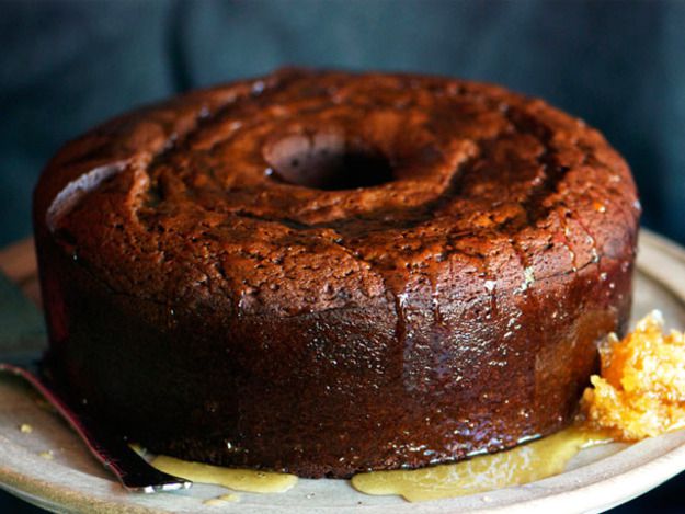 A dark golden honey cake drizzled with honey pooled on the plate.
