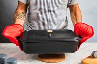someone using oxo oven mitts to hold a casserole dish