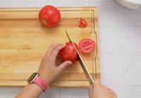 a person slicing a tomato