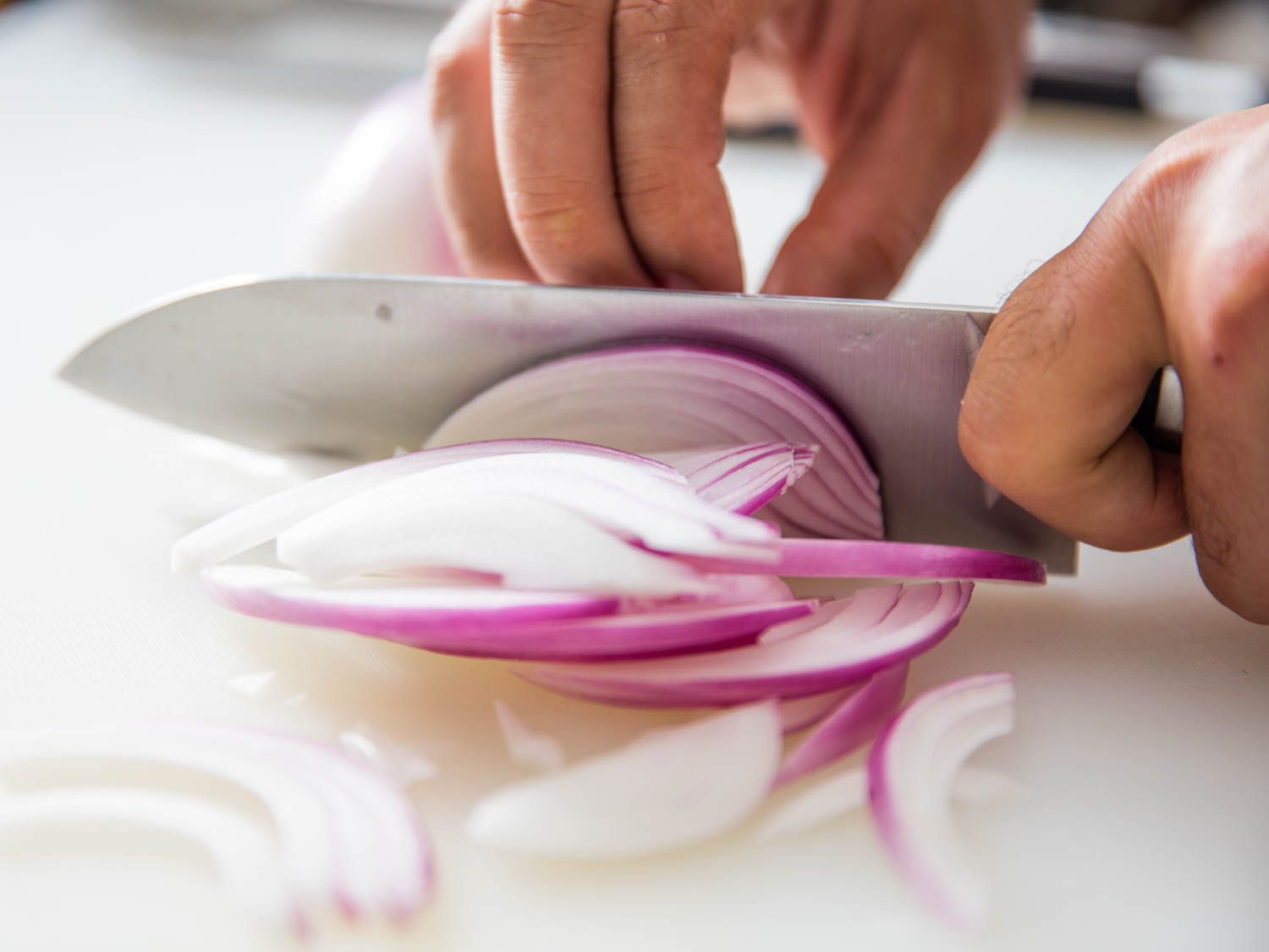 A knife slicing up a red onion.