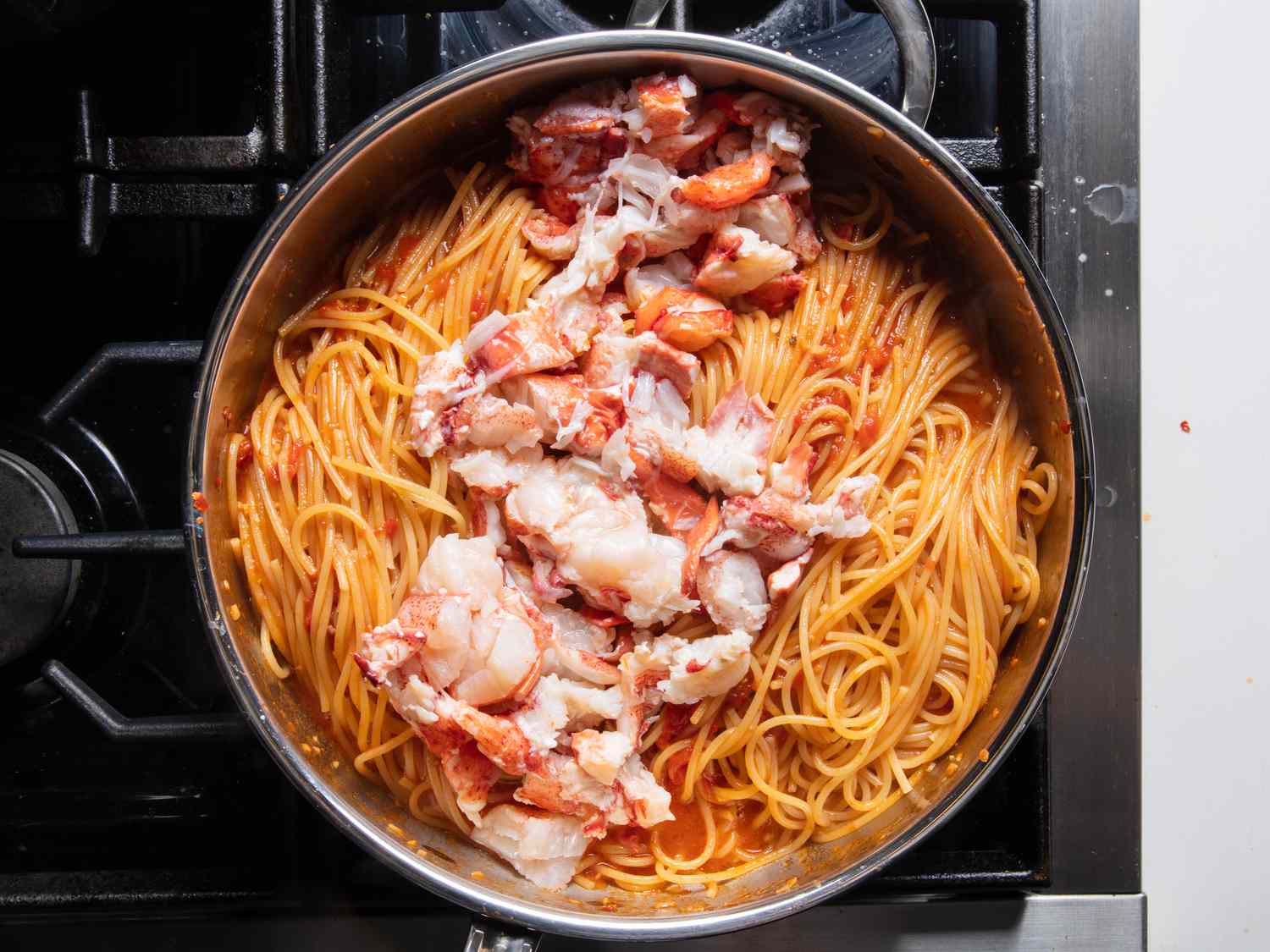 The par-cooked lobster meat sitting on top of the pasta, just before it gets stirred in. It looks very tender, a good sign it won't overcook once exposed to the pasta's heat.
