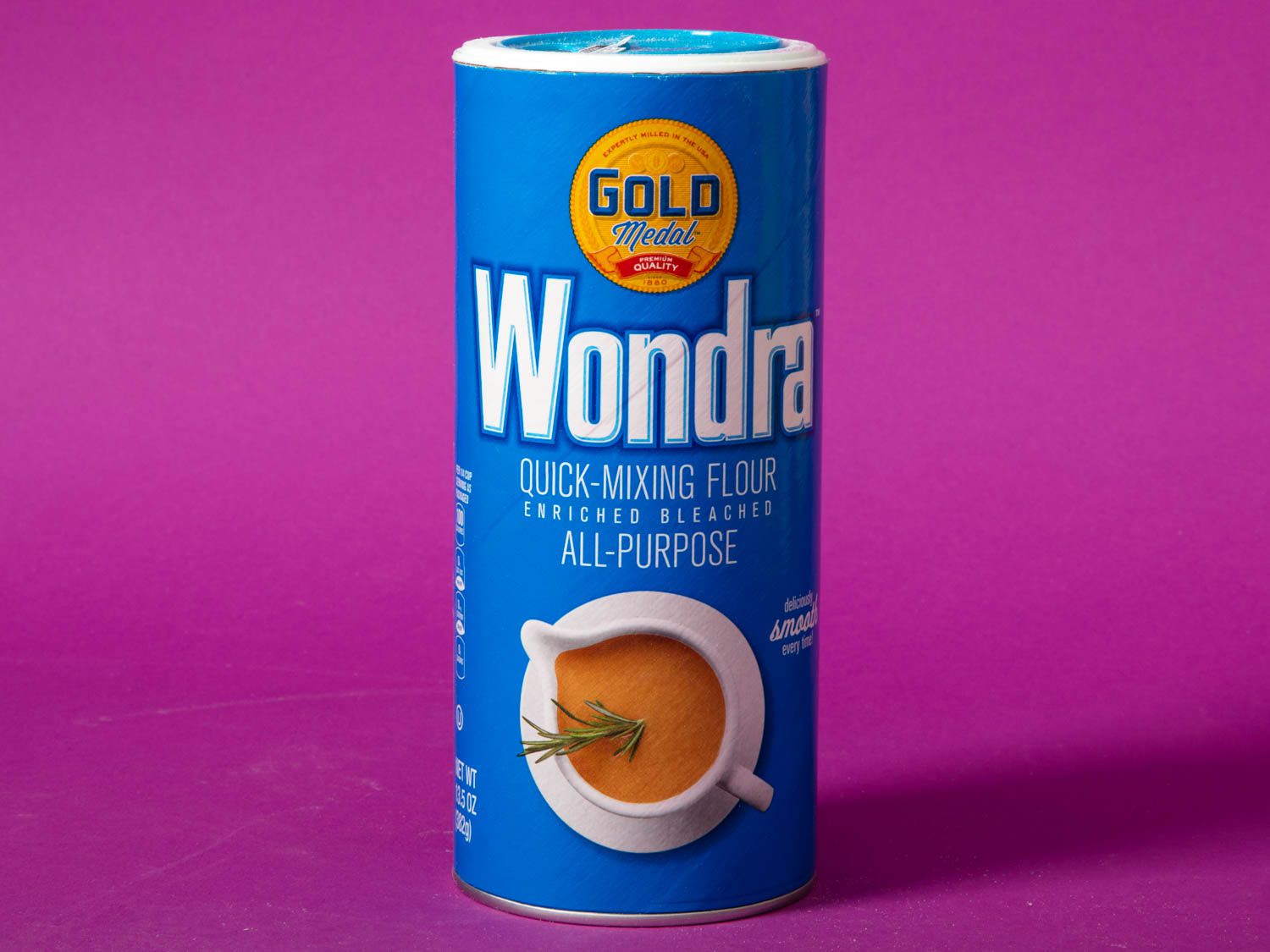 A container of Gold Medal Wondra Instant flour against a purple background.
