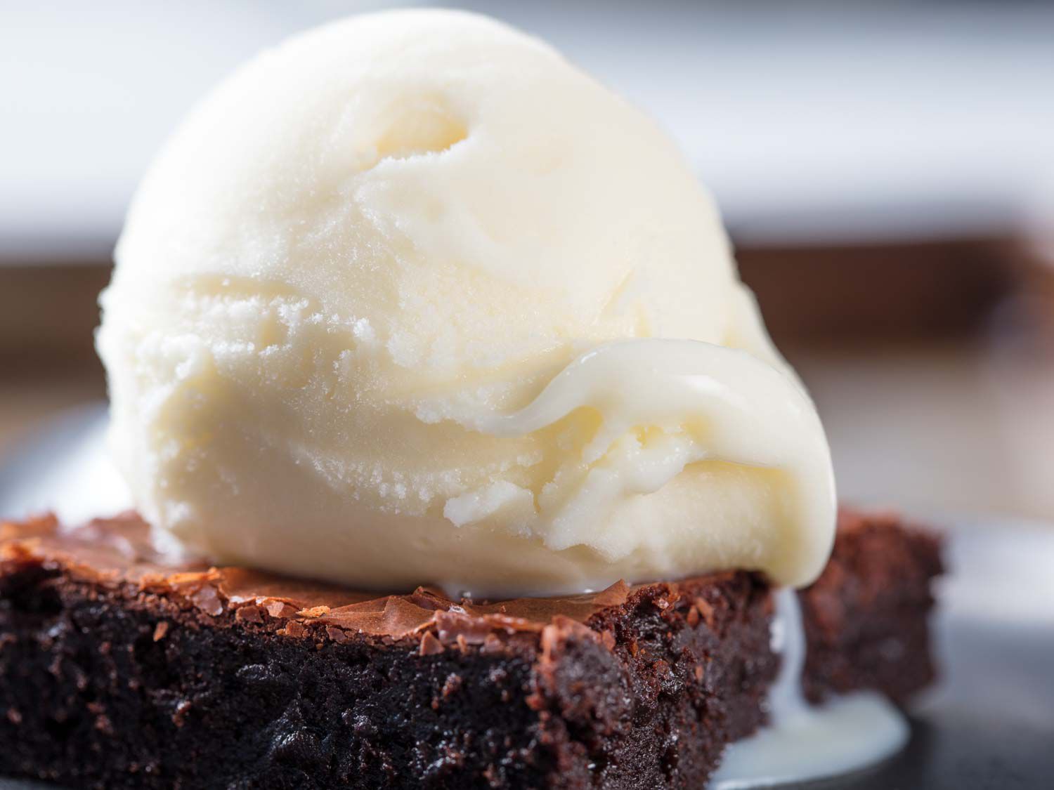 Closeup profile view of a vanilla ice milk, scooped and served atop a brownie square.