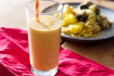 Mango lassi in a tall glass with a straw