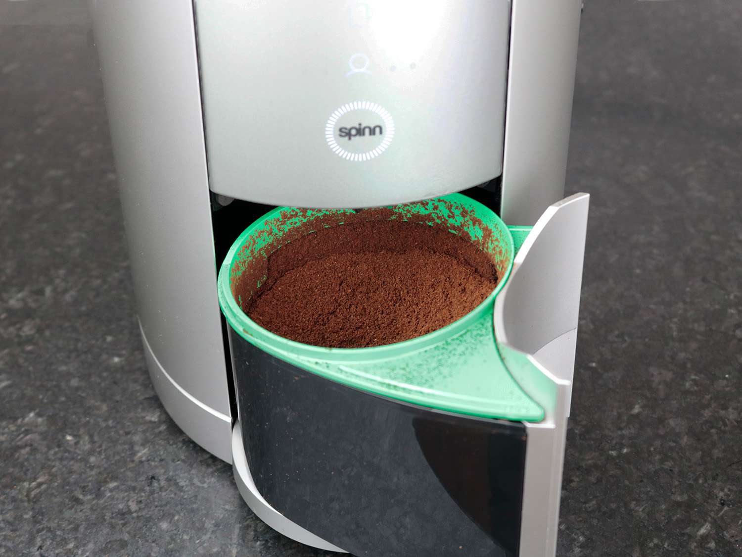 The grounds bin of the Spinn coffee maker with ground coffee in it