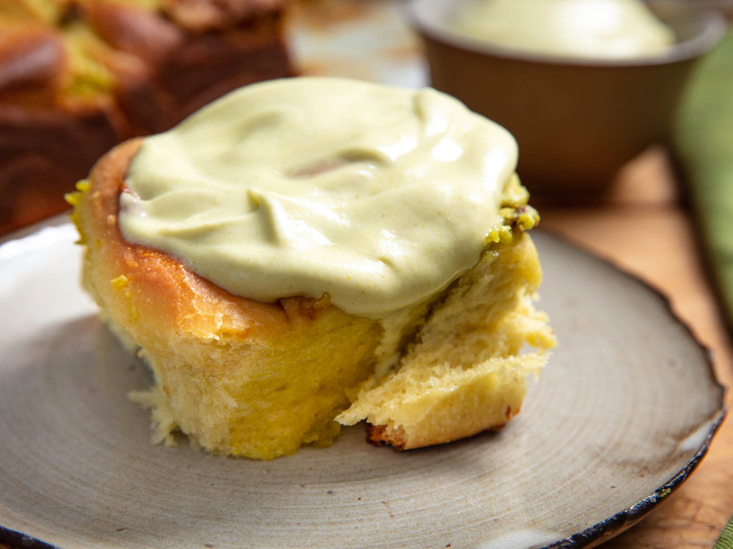 A fluffy pistachio bun with pistachio frosting melting across the top.