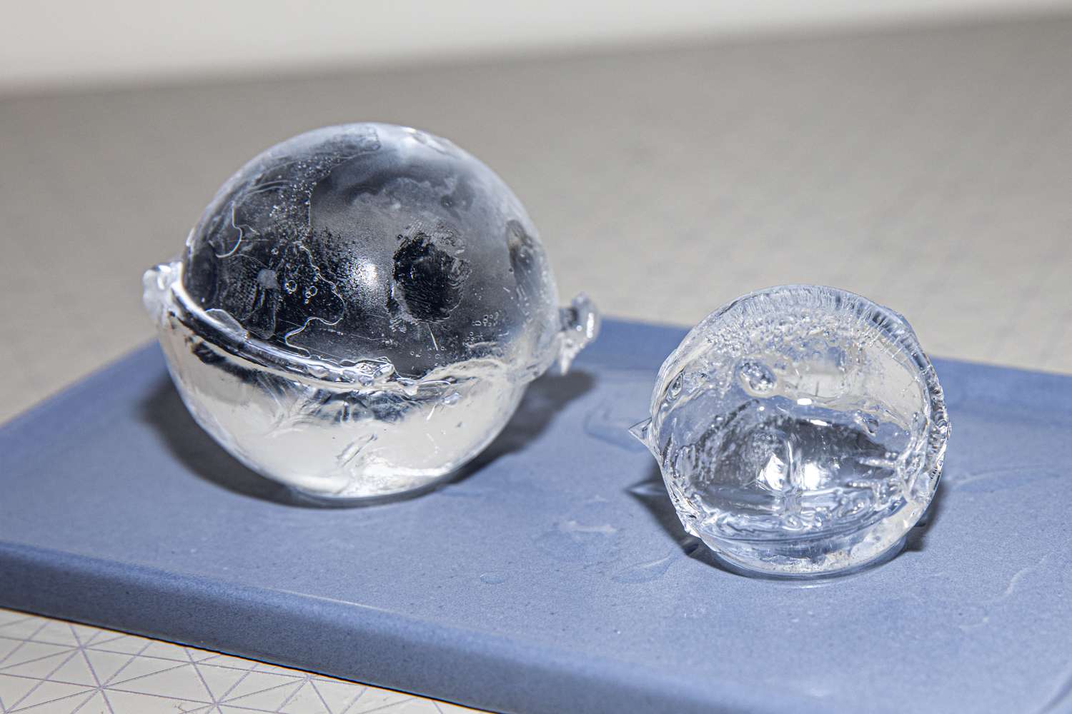 One small and one larger sphere ice side by side on a blue mat