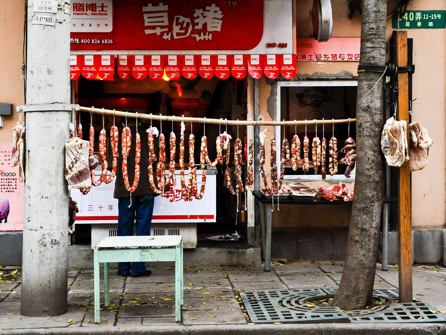 Cured sausage is hung from a pole in front of a shop to air-dry.