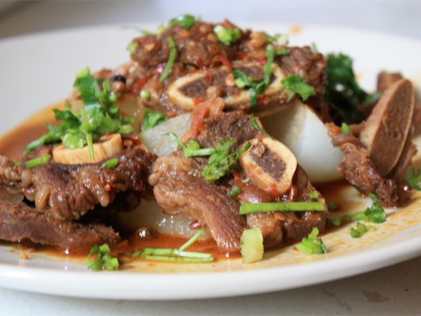 Sichuan red-braised beef on a serving plate, garnished with cilantro. 