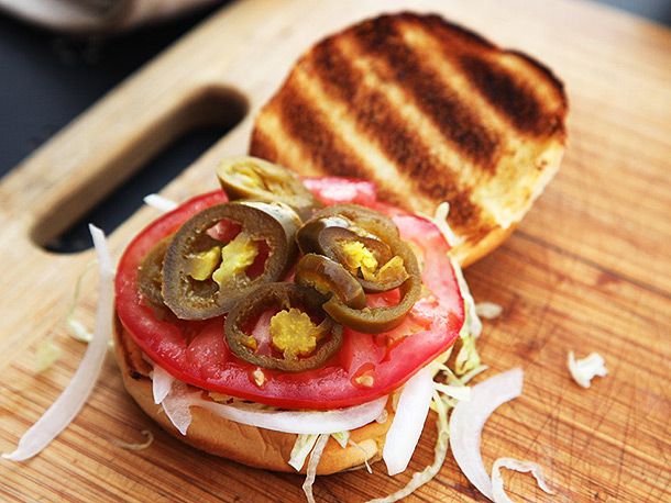 The prepared bun with toppings: lettuce, tomato, and jalapenos, waiting for the grilled burger.