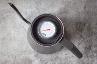 A kettle with an inset thermometer showing temperature viewed from above on a textured surface