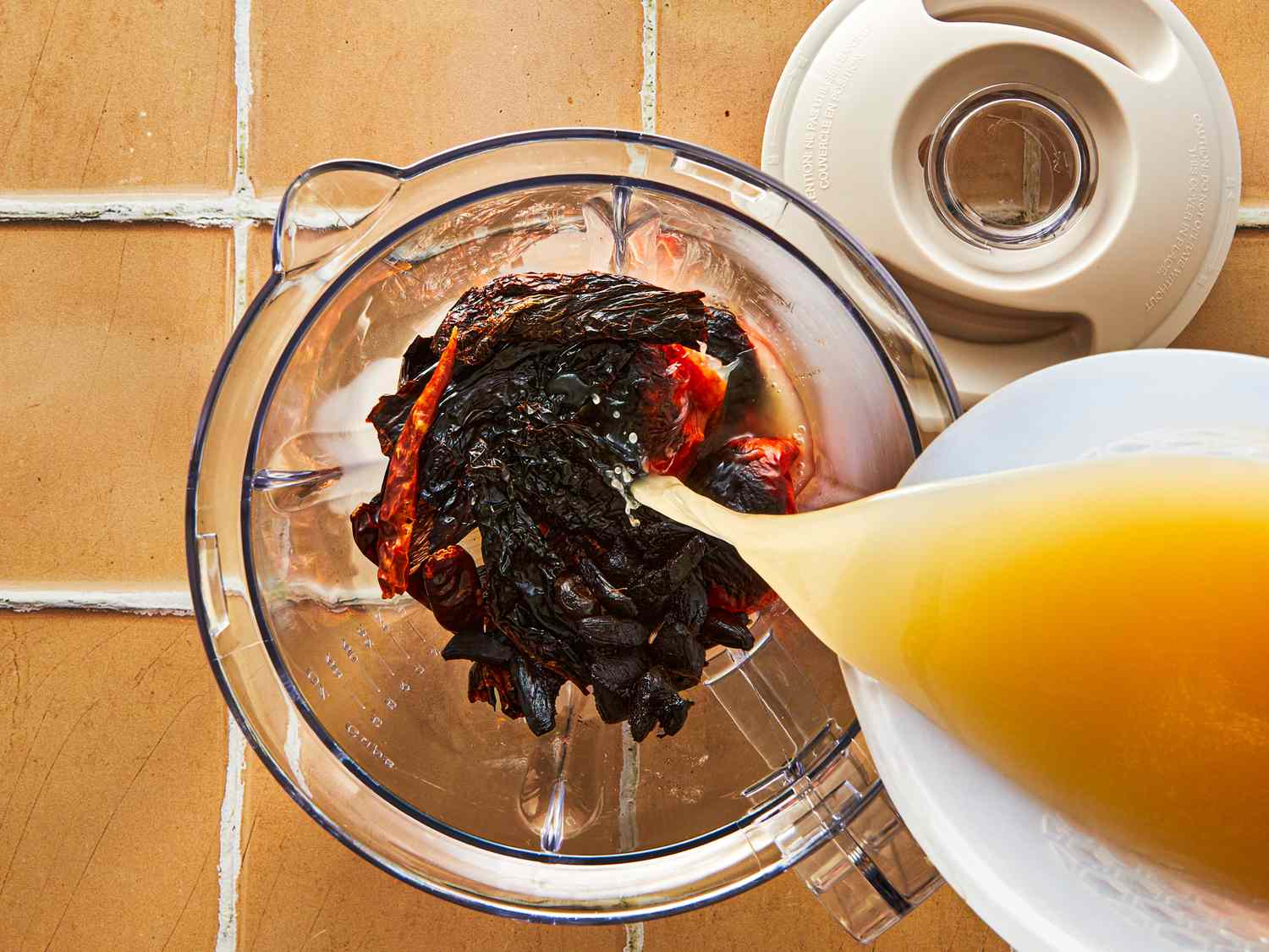 Food preparation showing dried ingredients and liquid being poured into a blender