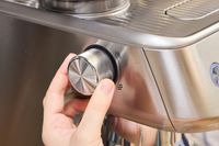 A person turns a dial on the side of the Breville The Oracle Jet Espresso Machine