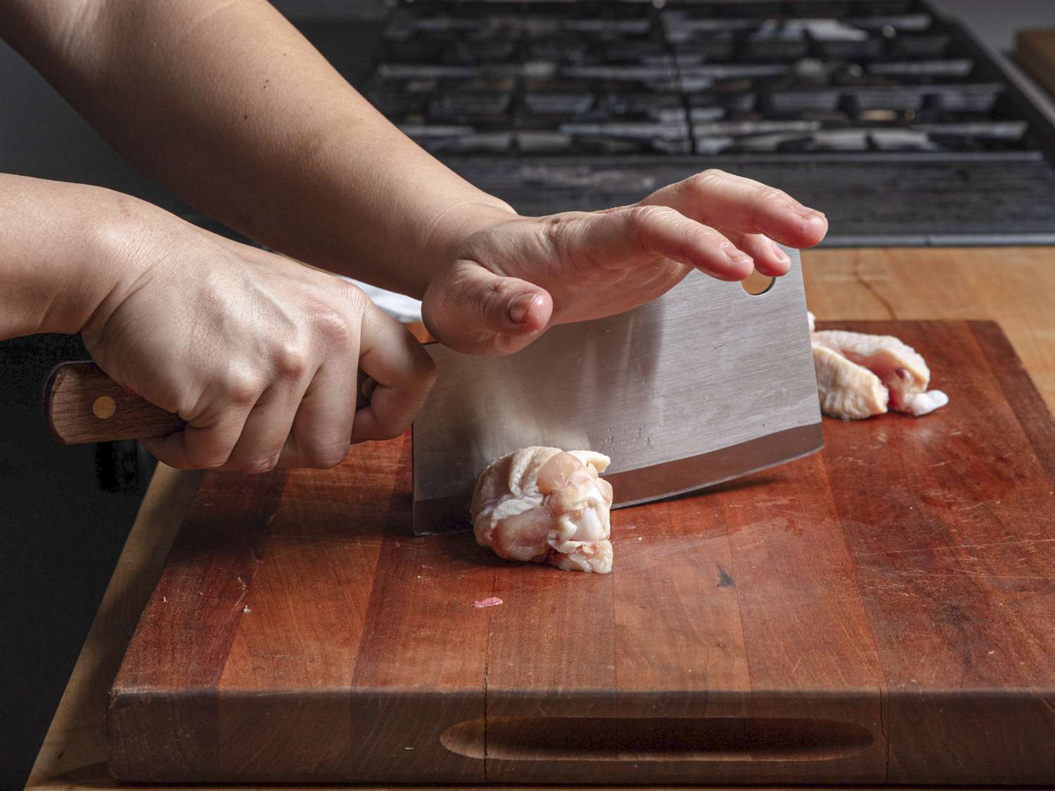 To demonstrate the slap cut, one hand holds the knife by ints handle while the other hand slaps down to push the blade through a chicken wing.