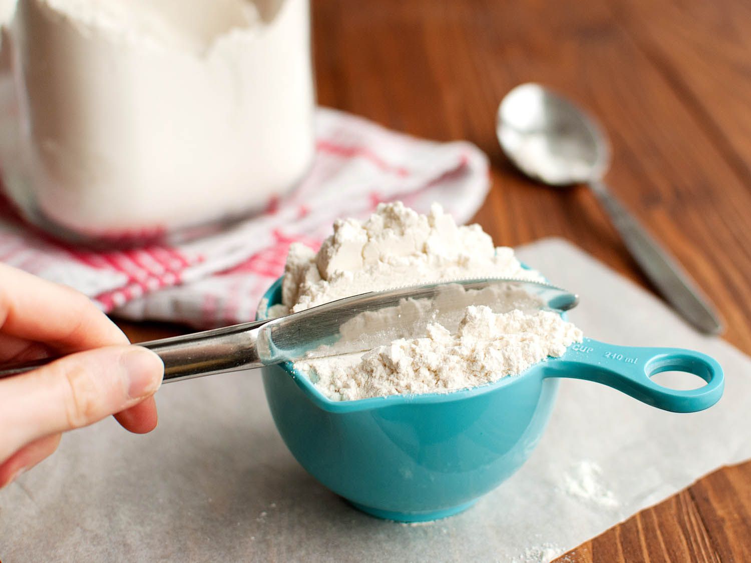 Author demonstrates how to sweep excess flour from the top of a measuring cup.
