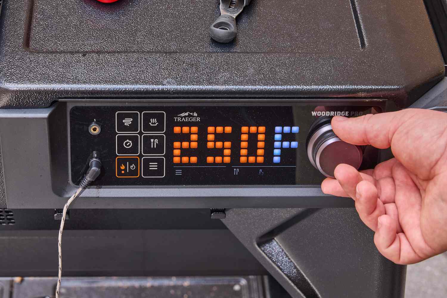 A person turns a dial on the Traeger Woodridge Pro