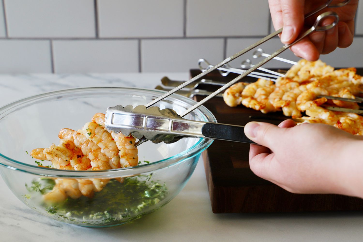 A person pulling shrimp off of the Norpro skewers.